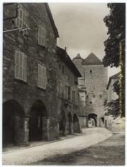 Villeneuve (Aveyron) : place à arcades (maisons des 14e et 15e siècles, rue pavée) et porte de ville carrée / J.-E. Auclair, Melot photogr. - [entre 1920 et 1950]. - Photographie