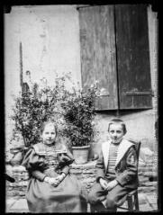 Portrait de deux enfants assis dans un jardin (une fille et un garçon). - [entre 1890 et 1920]. - Photographie