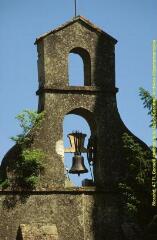 Plan rapproché du clocher-mur, vue de face [Clocher-mur à deux baies campanaires et une cloche. Les épaulements arrondis du premier niveau se retrouvent dans les clochers-murs à partir du XVIIIe siècle. Le niveau supérieur est formé par un simple pignon seul]. - Prise de vue du 19 mai 1998.