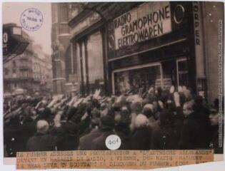 Le Führer adresse une proclamation à "l'Autriche allemande" devant un magasin de radio. A Vienne, des nazis saluent le bras levé en écoutant le discours du Führer / photographie Keystone, Paris. - 12 mars 1938. - Photographie
