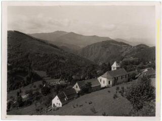 Hameau de Rieuprégon (Boussenac, Ariège) : maisons et église vues depuis la route du col de Port / J.-E. Auclair photogr. - [entre 1920 et 1950]. - Photographie