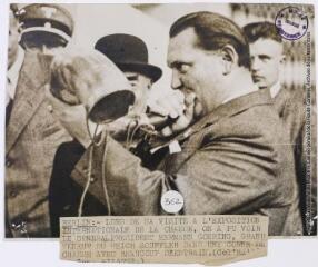 Berlin : lors de sa visite à l'exposition internationale de la chasse, on a pu voir le général président Hermann Goering, grand veneur du Reich souffler dans une corne de chasse avec beaucoup d'entrain / photographie The New York Times (Wide World Photos), Paris. - 28 octobre 1937. - Photographie