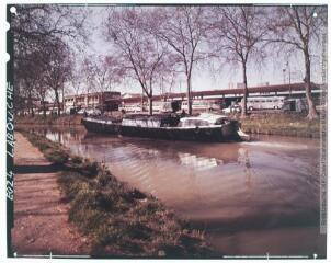 E 024. [Toulouse : péniche sur le canal devant la gare routière]. - Toulouse : maison Labouche frères, [après 1950]. - Photographie