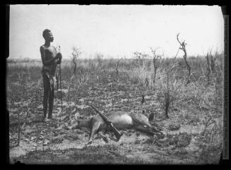 [Un chasseur avec sa pique. A ses pieds, un antilope mort et un fusil].