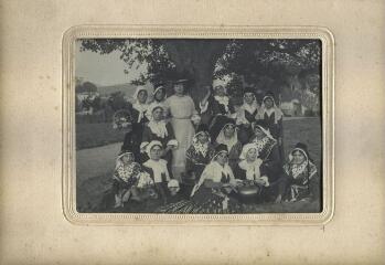 1 vue  - Portrait d\'un groupe de femmes en costumes traditionnels pyrénéens autour d\'une femme vêtue d\'une robe claire et d\'un grand chapeau sous un chêne. (ouvre la visionneuse)