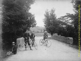 1 vue - Trois hommes avec leur bicyclette et un homme assis près d\'un pont. - [entre 1900 et 1920]. - Photographie (ouvre la visionneuse)
