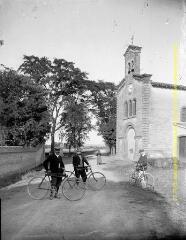 1 vue - Trois hommes avec leur bicyclette en pose devant l\'église du village. - [entre 1900 et 1920]. - Photographie (ouvre la visionneuse)