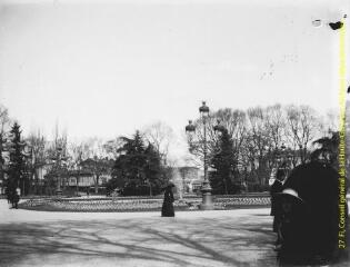 1 vue - Toulouse : jardin du Grand-Rond : promenade d\'une femme avec une ombrelle devant le bassin et le jet d\'eau. - [entre 1900 et 1920]. - Photographie (ouvre la visionneuse)
