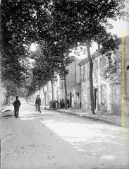 1 vue - Rue arborée : groupe devant une maison et passage d\'un cycliste. - [entre 1900 et 1920]. - Photographie (ouvre la visionneuse)