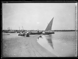 1 vue  - Trois femmes sur la plage (Mme Mauran et ses soeurs) et bateaux à voile. - 1901. - Photographie (ouvre la visionneuse)