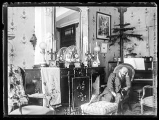 1 vue  - Intérieur de la maison Mauran : coin salon : un homme assoupi dans un fauteuil. - [entre 1901 et 1909]. - Photographie (ouvre la visionneuse)