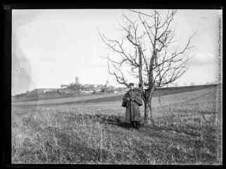 1 vue  - Montcuq : portrait d\'un officier dans un champ, avec en arrière-plan le village. - mars 1916. - Photographie (ouvre la visionneuse)