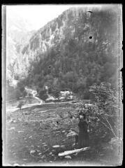 1 vue  - Luchonnais ? Une femme dans un paysage de montagne (vallée et hauts sommets). - 1906. - Photographie (ouvre la visionneuse)