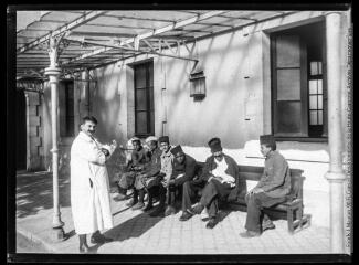 1 vue  - Hôpital temporaire n° 23 (lycée Gambetta) : soldats convalescents assis sous une galerie. - 1915-1916. - Photographie (ouvre la visionneuse)