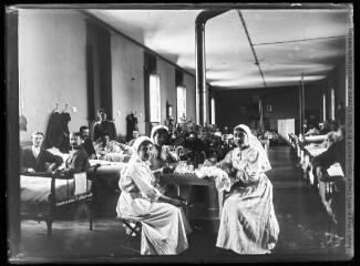 1 vue  - Hôpital temporaire n° 23 : dans une chambre commune (salle III), trois infirmières et les lits occupés. - 1915. - Photographie (ouvre la visionneuse)