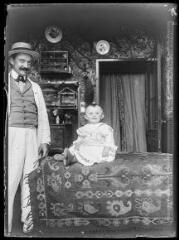 1 vue  - Portrait en intérieur d\'un homme et d\'un enfant en bas âge assis sur un tapis. - [entre 1890 et 1920]. - Photographie (ouvre la visionneuse)