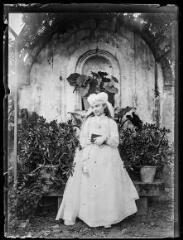 1 vue  - Portrait d\'une jeune fille en communiante (Anne Antarieu) dans un décor de plantes. - [entre 1890 et 1920]. - Photographie (ouvre la visionneuse)