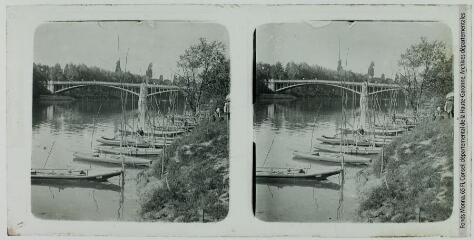 1 vue - [Barques amarrées le long d\'une berge de rivière et pont métallique en arrière-plan]. - [entre 1920 et 1950]. - Photographie (ouvre la visionneuse)