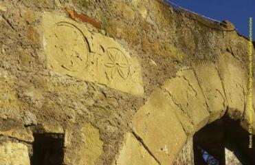 1 vue  - Plan rapproché d\'un fragment de sarcophage encastré dans le mur gouterreau sud, au-dessus d\'une porte, vue en contre-plongée [Ce fragment de sarcophage est orné d\'un chrisme et d\'une rosace sculptés]. - Prise de vue du 8 avril 1999. (ouvre la visionneuse)