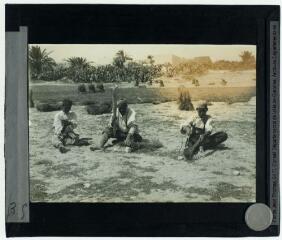 2 vues 35. Iles Kerkennah. Un indigène, muni d'une sorte de long battoir, frappe les minces tiges d'alfa pour les rendre plus souples encore. A gauche, un jeune garçon les tresse par un mouvement spécial de ses mains. A droite, un autre enroule les cordages destinés à l'exportation. Les pêcheurs utilisent en outre, l'alfa pour la fabrication des filets.